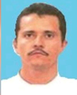 Uma foto de identificação de um homem de meia-idade com cabelos castanhos curtos e bigode. Ele está posicionado de frente contra um fundo azul sólido e veste o que parece ser uma camiseta branca. A imagem apresenta uma qualidade de resolução baixa e está levemente desfocada nas bordas laterais.