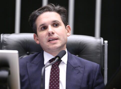 Hugo Motta sentado na cadeira de presidente da Câmara