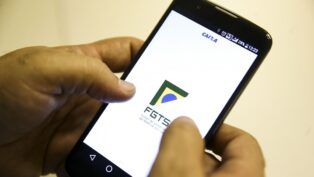 Mão segura celular com aplicativo do FGTS na tela
