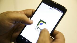 Mão segura celular com aplicativo do FGTS na tela