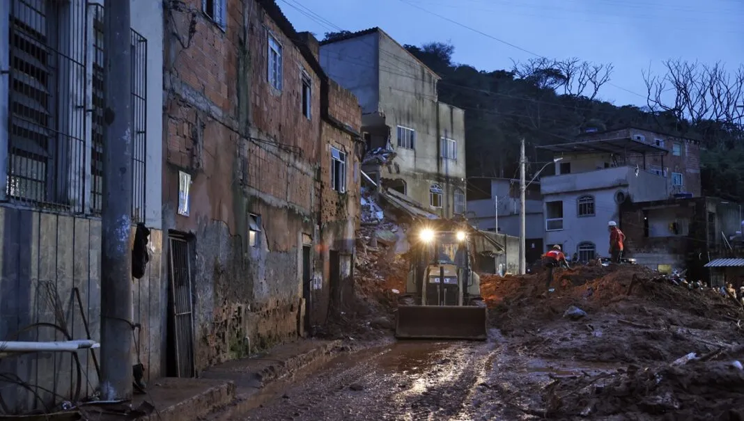 Soldados do Corpo de Bombeiros e voluntários fazem busca e resgate de pessoas em escombros de casas soterradas por lama após fortes chuvas