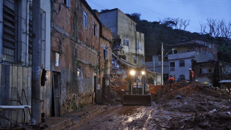 Soldados do Corpo de Bombeiros e voluntários fazem busca e resgate de pessoas em escombros de casas soterradas por lama após fortes chuvas