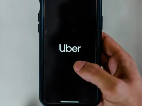 Uma mão mexe em um celular com o aplicativo da Uber na tela