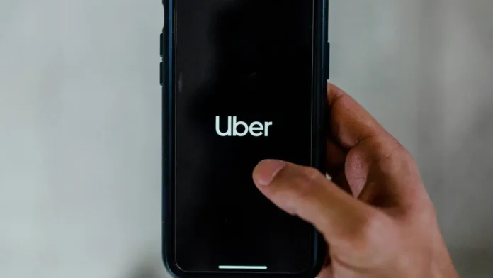Uma mão mexe em um celular com o aplicativo da Uber na tela