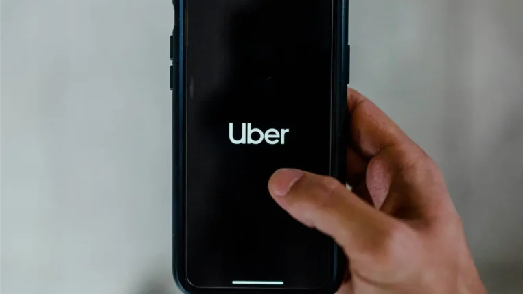 Uma mão mexe em um celular com o aplicativo da Uber na tela