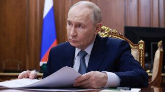 Putin está sentado segurando alguns papéis