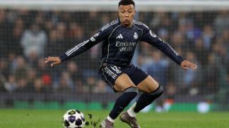 Mbappé flexiona os dois joelhos ao dominar a bola em campo