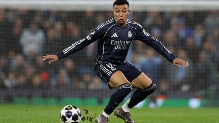 Mbappé flexiona os dois joelhos ao dominar a bola em campo