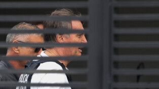 Jair Bolsonaro chega a sua casa e é visto através das frestas do portão