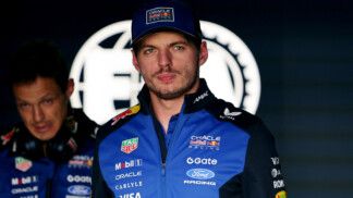 Max Vertappen usa uniforme da Red Bull e aparece logo à frente do logo da FIA