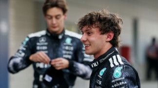 Kimi Antonelli sorri em primeiro plano enquanto George Russell aparece ao fundo