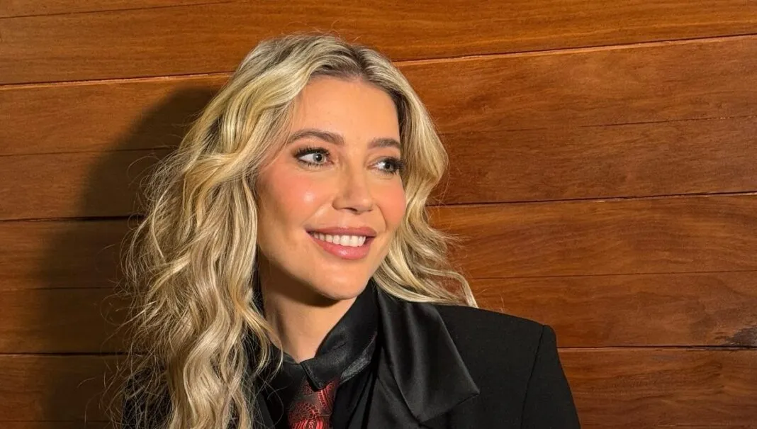 Luiza Possi sorri em foto posada, vestindo paletó, camisa preta e gravata