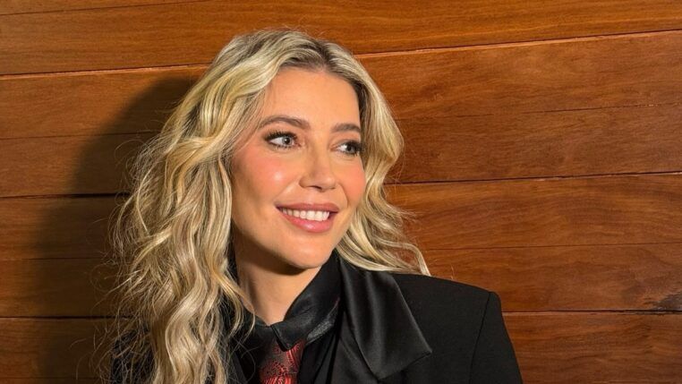 Luiza Possi sorri em foto posada, vestindo paletó, camisa preta e gravata