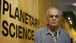 Carlos Nobre posa para foto à frente de painel com a informação "Ciência planetária", em inglês