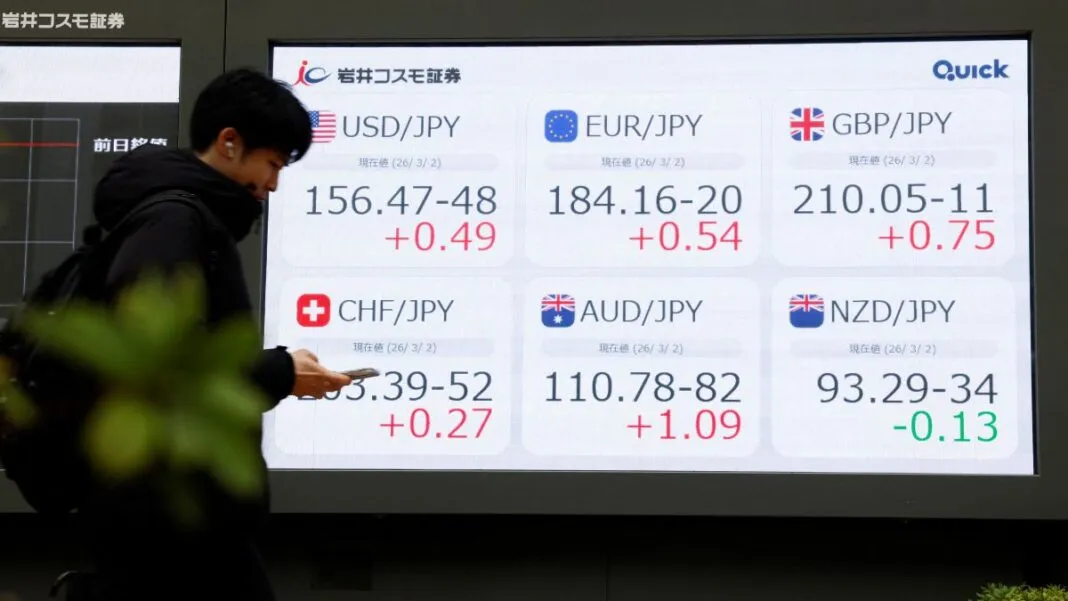 Pessoa olha o celular diante de painel com números do mercado de ações