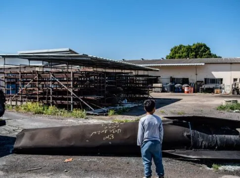 Um menino observa os destroços de um míssil iraniano que caiu em um kibutz, após o Irã lançar ataques com mísseis em resposta aos ataques dos EUA e de Israel.