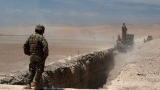 Membro do exército chileno observa uma trincheira cavada por máquinas pesadas em Arica, perto da fronteira com o Peru (Foto: Alexander Infante/Reuters)