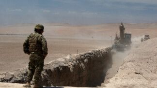 Membro do exército chileno observa uma trincheira cavada por máquinas pesadas em Arica, perto da fronteira com o Peru (Foto: Alexander Infante/Reuters)