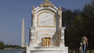 Uma estátua representando um grande vaso sanitário dourado, intitulada "Um Trono Digno de um Rei", está exposta perto do Lincoln Memorial, no National Mall, em Washington, D.C., EUA