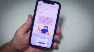 Uma mão segura um celular, cuja tela mostra o site do Prouni