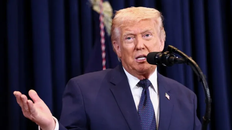 Donald Trump gesticula com a mão direita enquanto fala ao microfone