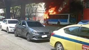 Ônibus em chamas ao lado de carros na rua