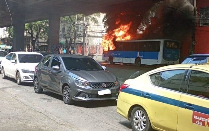 Ônibus em chamas ao lado de carros na rua
