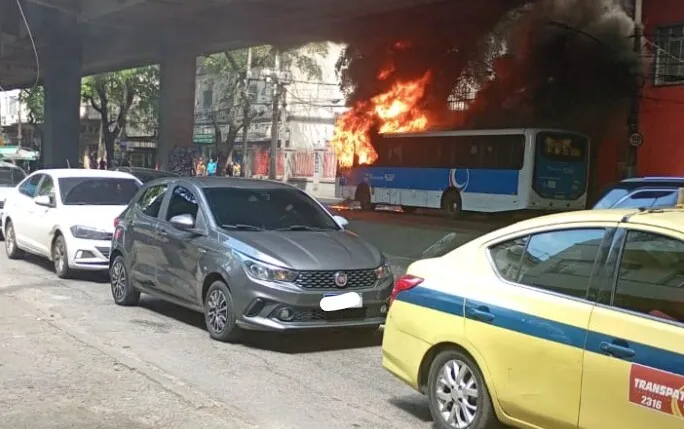 Ônibus em chamas ao lado de carros na rua