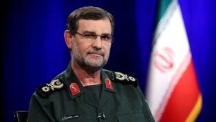 Alireza Tangsiri posa para foto, à frente da bandeira do Irã