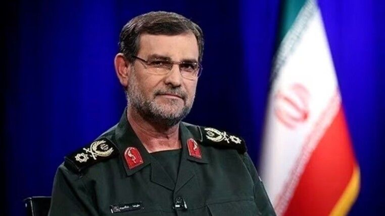 Alireza Tangsiri posa para foto, à frente da bandeira do Irã