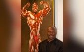 Lee Haney veste terno preto e aparece à frente de uma foto antiga sua, na época de competições
