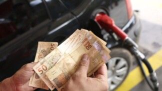 Frentista conta dinheiro enquanto carro é abastecido em posto
