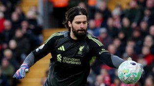 Alisson pega a bola de futebol com a mão direita