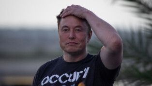 Elon Musk passa a mão esquerda no cabelo olhando para a frente