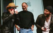 Bono Vox, vocalista do U2, brinca com aparelhos da Apple ao lado de Steve Jobs e do guitarrista The Edge.