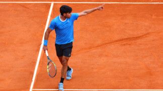 Alcaraz segura raquete e aponta para o lado durante jogo no saibro