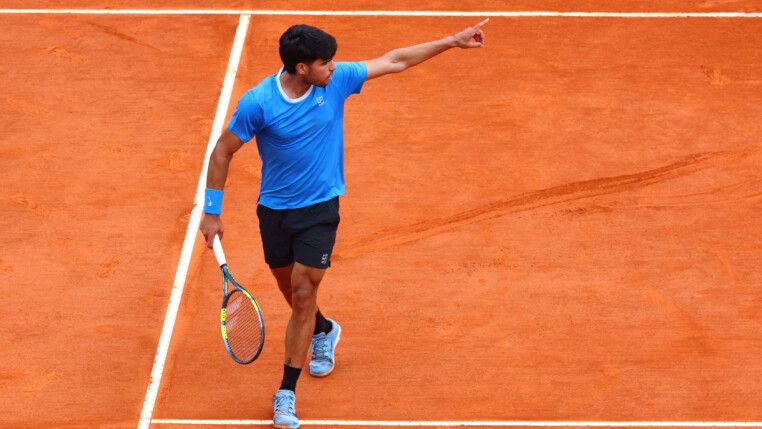 Alcaraz segura raquete e aponta para o lado durante jogo no saibro