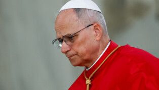 Papa apresenta vestes vermelhas e olha para baixo