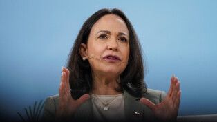 María Corina gesticula enquanto fala ao microfone