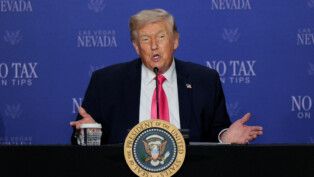 Donald Trump abre os braços enquanto fala ao microfone durante discurso