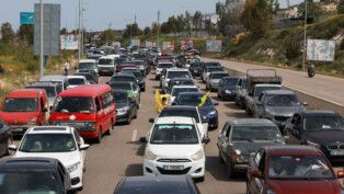Carros enfileirados no trânsito, uns com bandeiras e gestos de motoristas