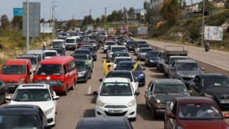 Carros enfileirados no trânsito, uns com bandeiras e gestos de motoristas