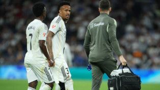 Militão anda no gramado na companhia do médico do Real Madrid