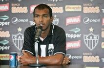 Richarlyson está sentado em frente ao microfone, com os braços cruzados