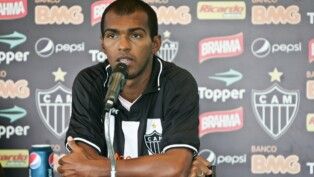 Richarlyson está sentado em frente ao microfone, com os braços cruzados