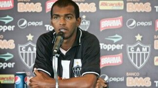 Richarlyson está sentado em frente ao microfone, com os braços cruzados