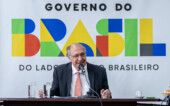 Geraldo Alckmin fala com a imprensa, à frente de um banner do governo federal
