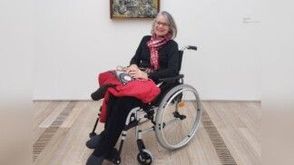 Célia está numa cadeira de rodas à frente de um quadro no museu