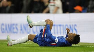 Estêvão está caído no gramado com a mão no joelho esquerdo