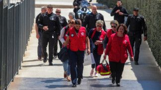 Equipes de resgate e policiais caminham em frente ao Tribunal de Apelação de Atenas após o ataque.